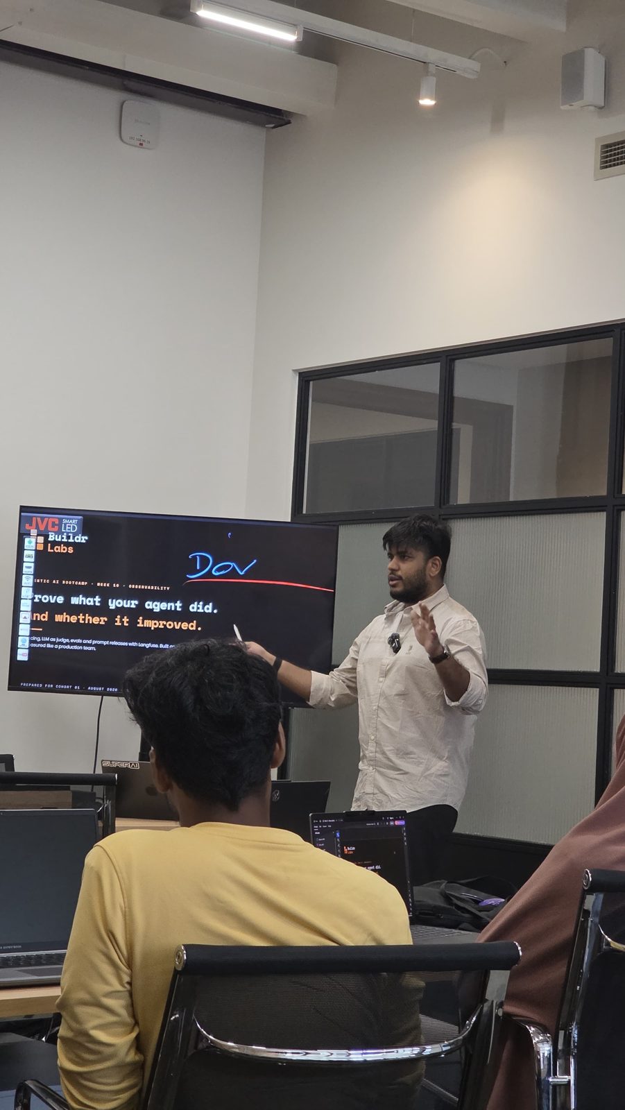 Isuru walking a cohort through a live demo in a glass-walled room